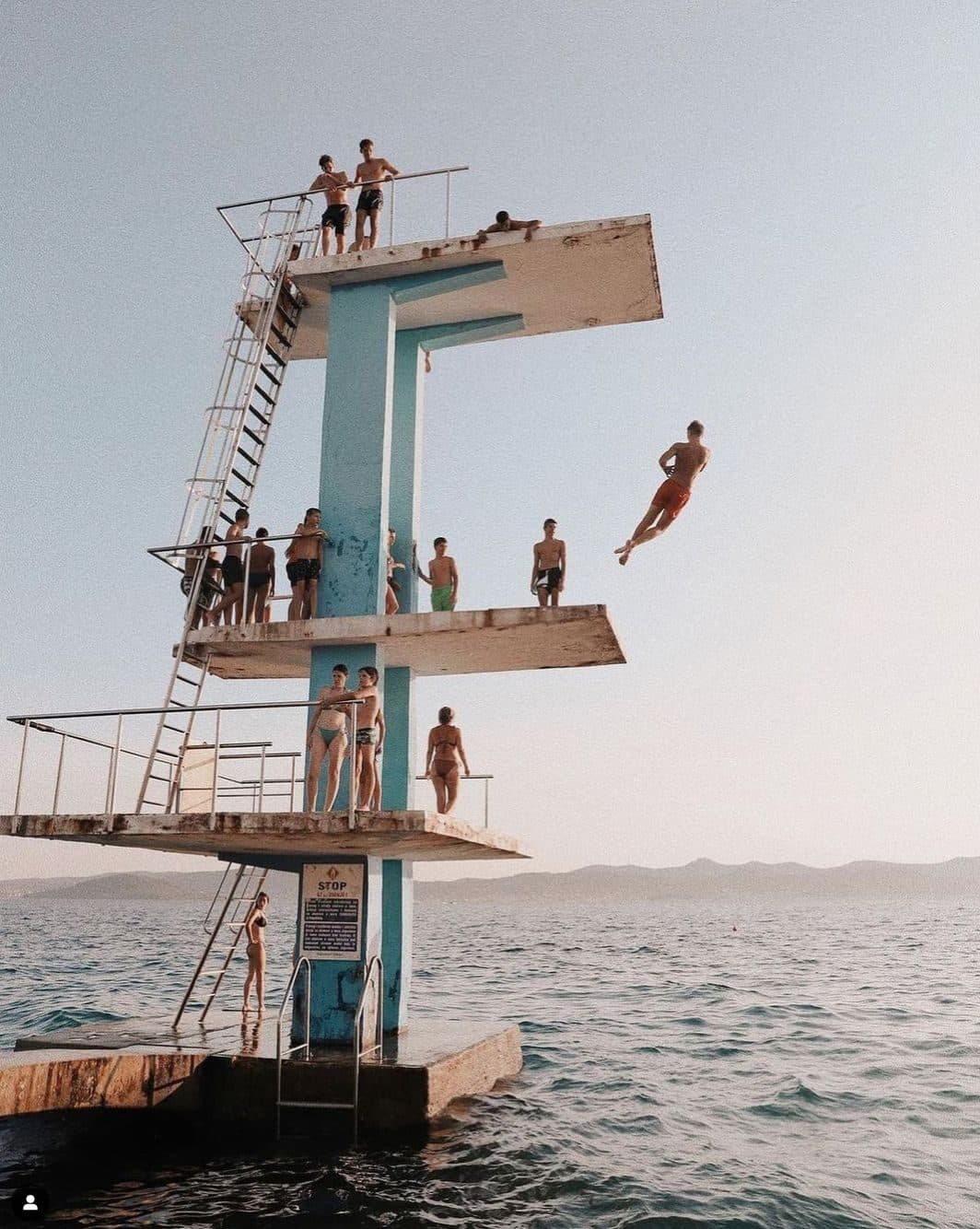 Swimmers gathered around a seaside diving platform